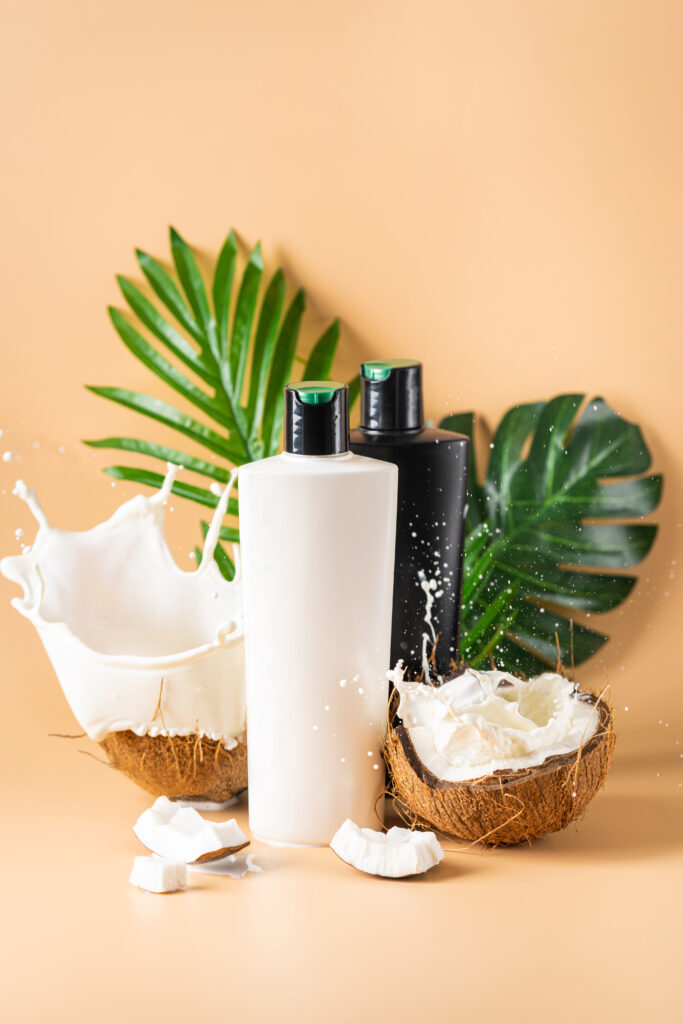 Bottle of hair shampoo and fresh organic coconut , natural cosmetic on light orange background. hair conditioner ingredients