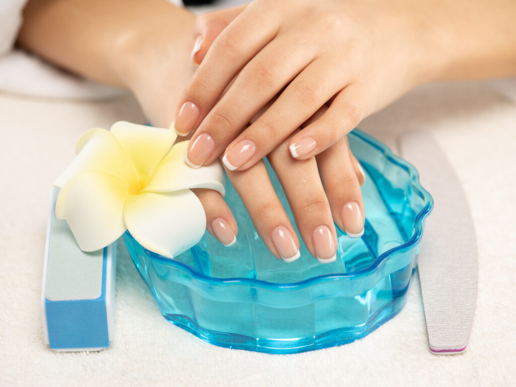 Woman gets manicure procedure in a spa salon. Beautiful female hands. Hand care. Woman cares for the nails on hands. Beauty treatment with skin of hand.   Woman's hands close-up view. Remove OPI Gel Polishes