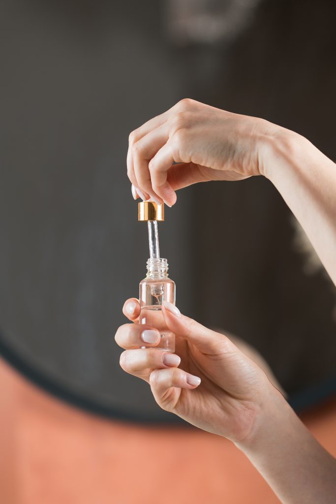 A woman holds a dropper and dropper with a drop of moisturizing serum for face and body skin care. Skin care concept. Anti-aging care.