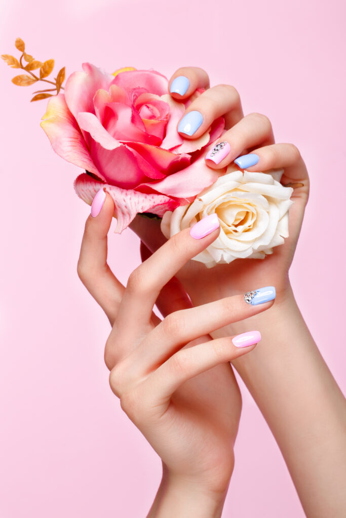 Trending Nail Art Styles for 2025. Beautiful pink and blue manicure with crystals on female hand. Close-up. Nail Trends for 2025