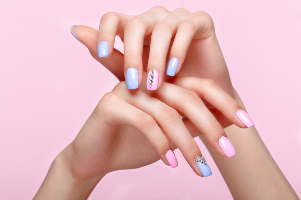 Trending Colors for 2025. Beautiful pink and blue manicure with crystals on female hand. Close-up. Picture taken in the studio