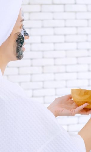 Beautiful young woman in white bathrobe applying a revitalizing