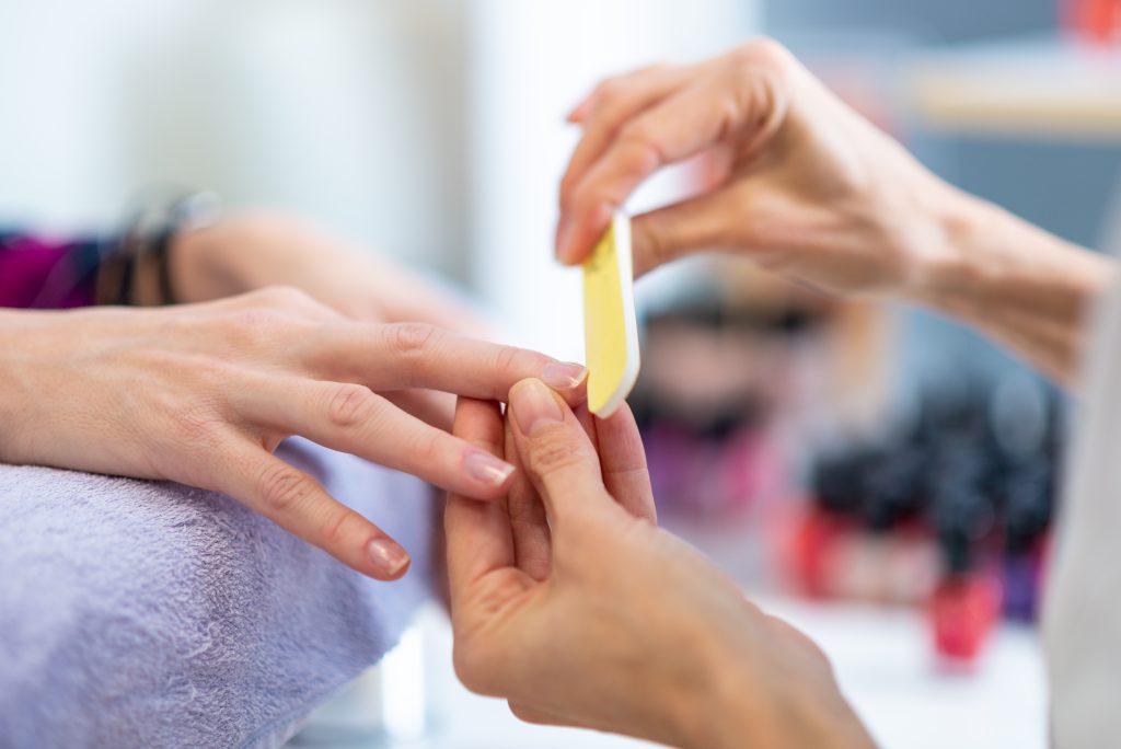 Closeup of professional manicurist filing finger nails.