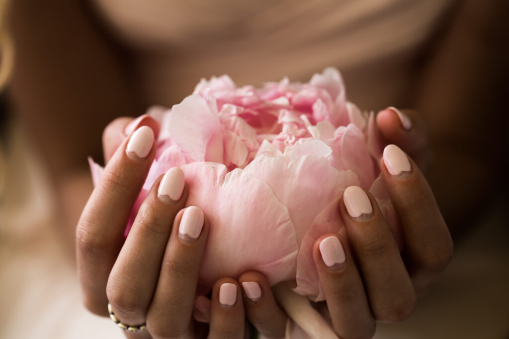 Nail Care Must-Haves. girl with a beautiful delicate manicure holding flower peonies