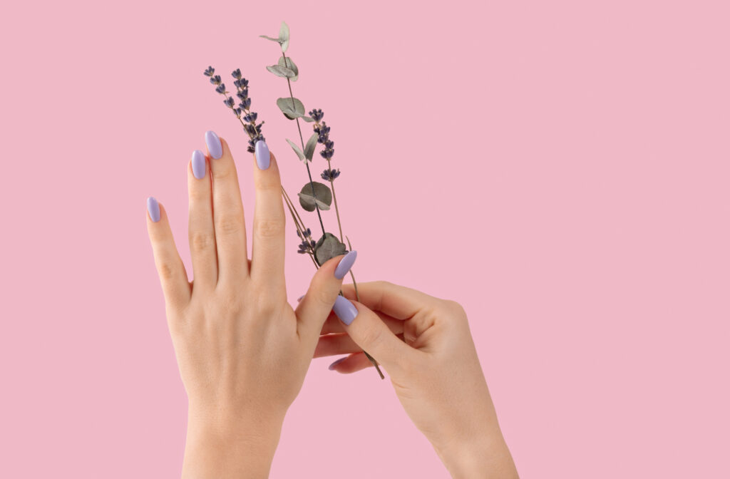 Top Nail Shapes for 2025. Hands of a beautiful well-groomed with feminine violet lavender nails gel polish on a pink background eucalyptus branches. Manicure, pedicure beauty salon concept. Nail Trends for 2025