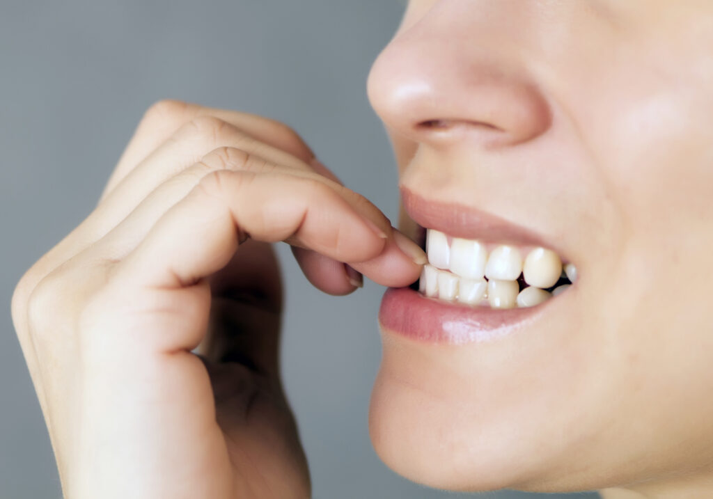 Causes of Nail Biting. Nervous young woman biting her nails