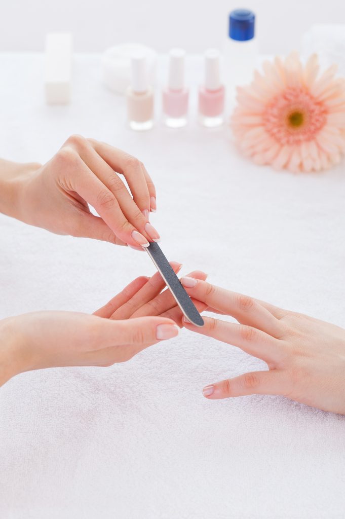 all-day care: from hair to toes! Preparing nails for manicure. Close-up of beautician polishing nails of female customer