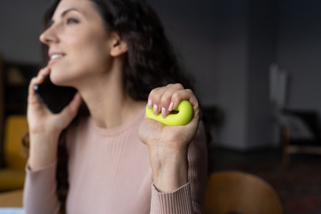 Young smiling female employee squeezing grip ring, practicing hand and wrist exercises at work. Alternative Habits to Replace Nail Biting