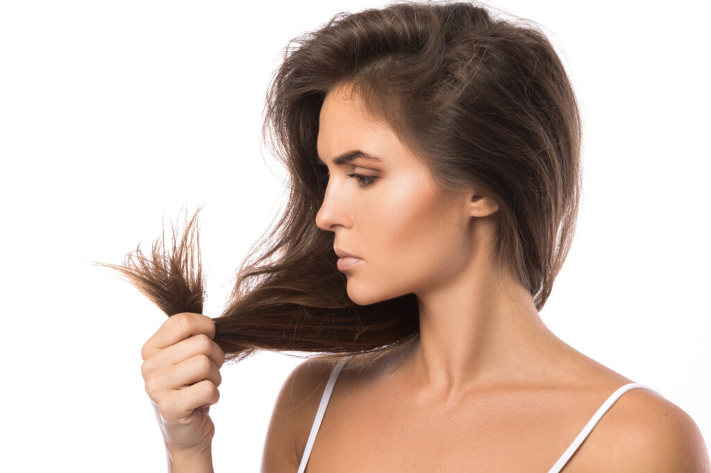 Hair Split Ends Treatment. Easy Home Fixes. Young woman is unhappy with split ends of her hair