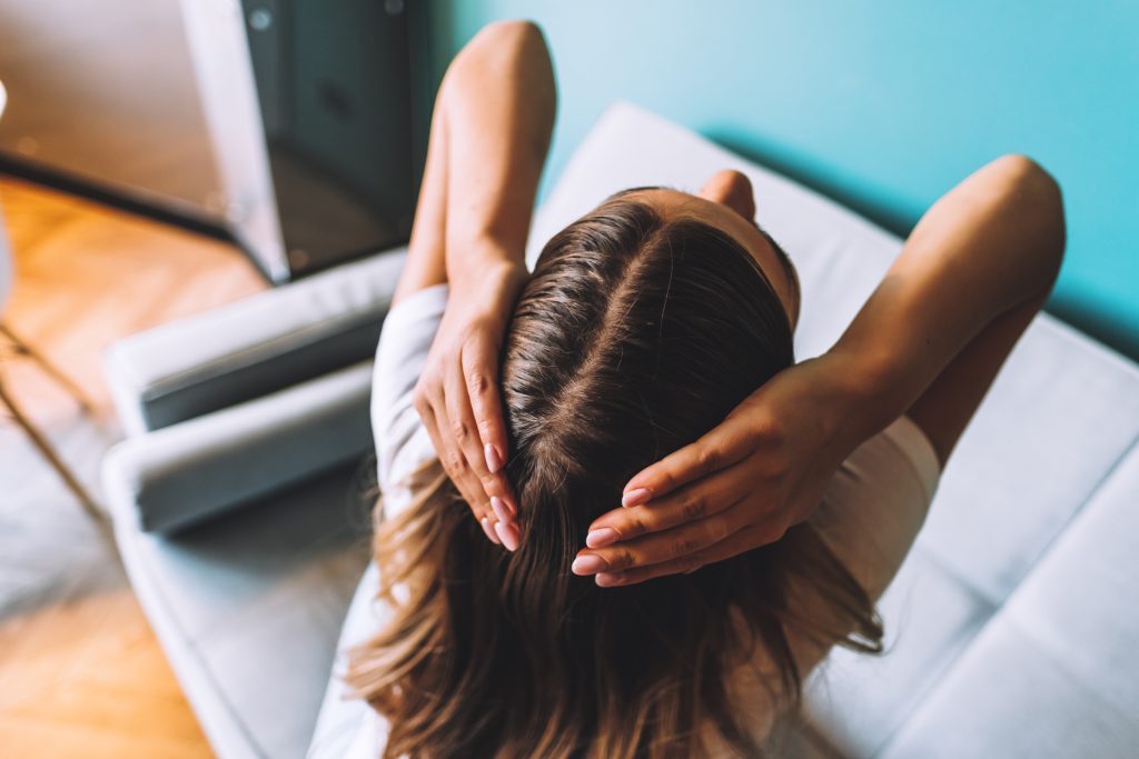 Young brunette woman showing her scalp, hair roots, color, grey hair, hair loss or dry scalp problem. Regular Scalp Massages for Hair Growth