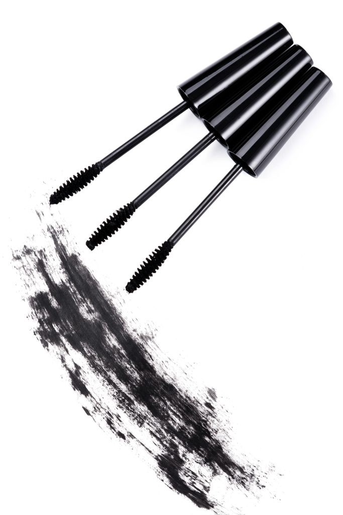 Brushes and smudged mascara on white background