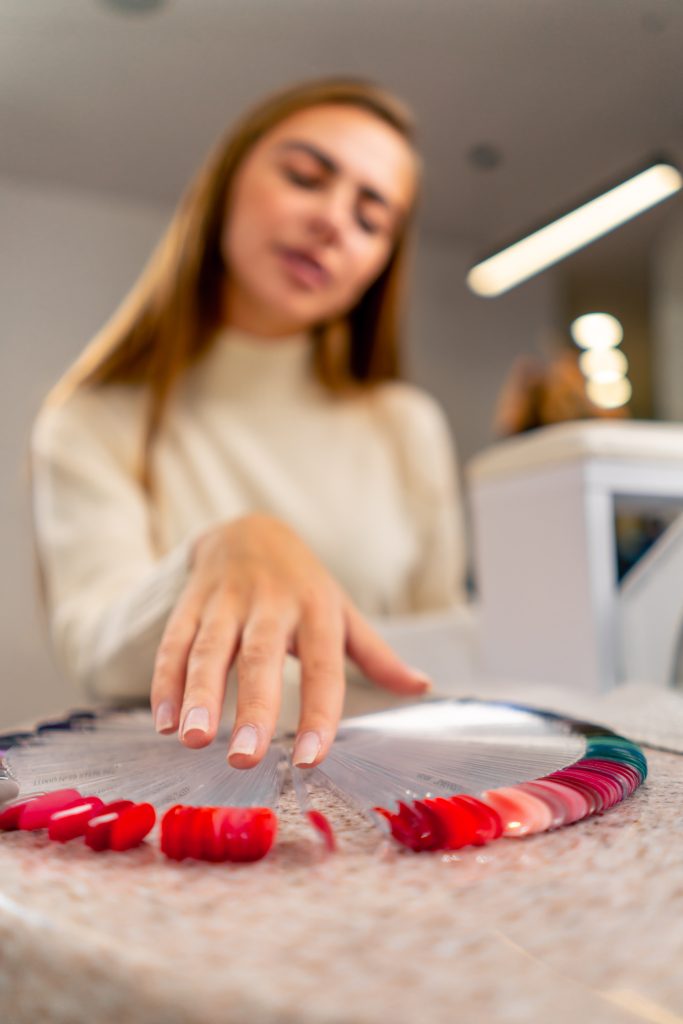 close-up of a girl in a beauty salon chooses color nail polish during a manicure a large palette