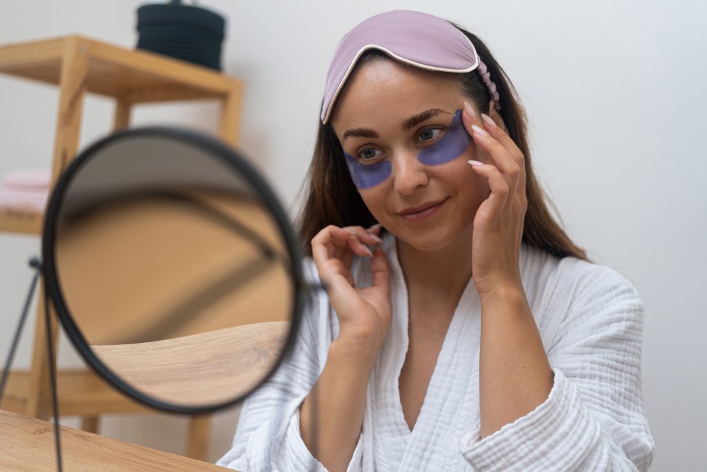 Complete Eye Care Routine at Home. Eye Patch Magic: A woman's morning delight as she looks in the mirror, applying under-eye masks for puffiness, wrinkles, and dark circles.