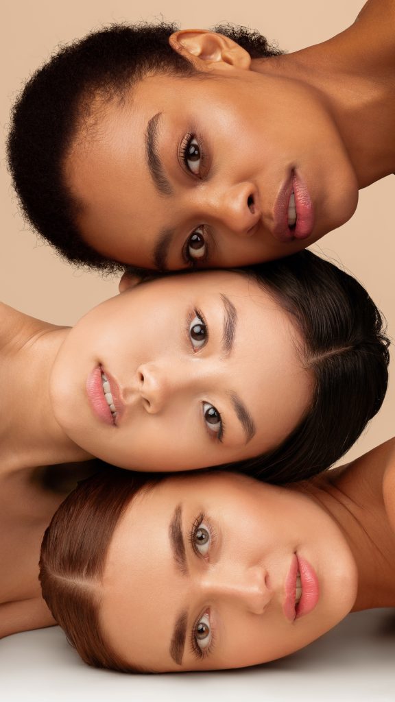 Beauty. Portrait Of Three Multiethnic Models Girls With Perfect Face Skin Posing Over Gray Studio Background. Vertical Panorama