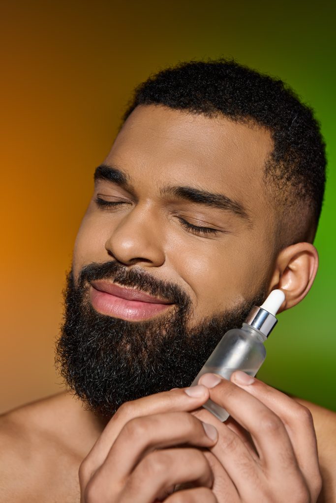 African american handsome man holds serum. beard care.