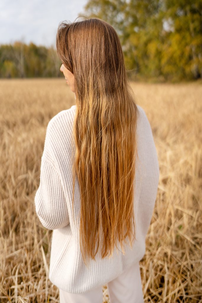 A woman stands gracefully in a golden wheat field, showcasing her flowing hair while enjoying natures beauty. Natural Remedies for Hair Growth