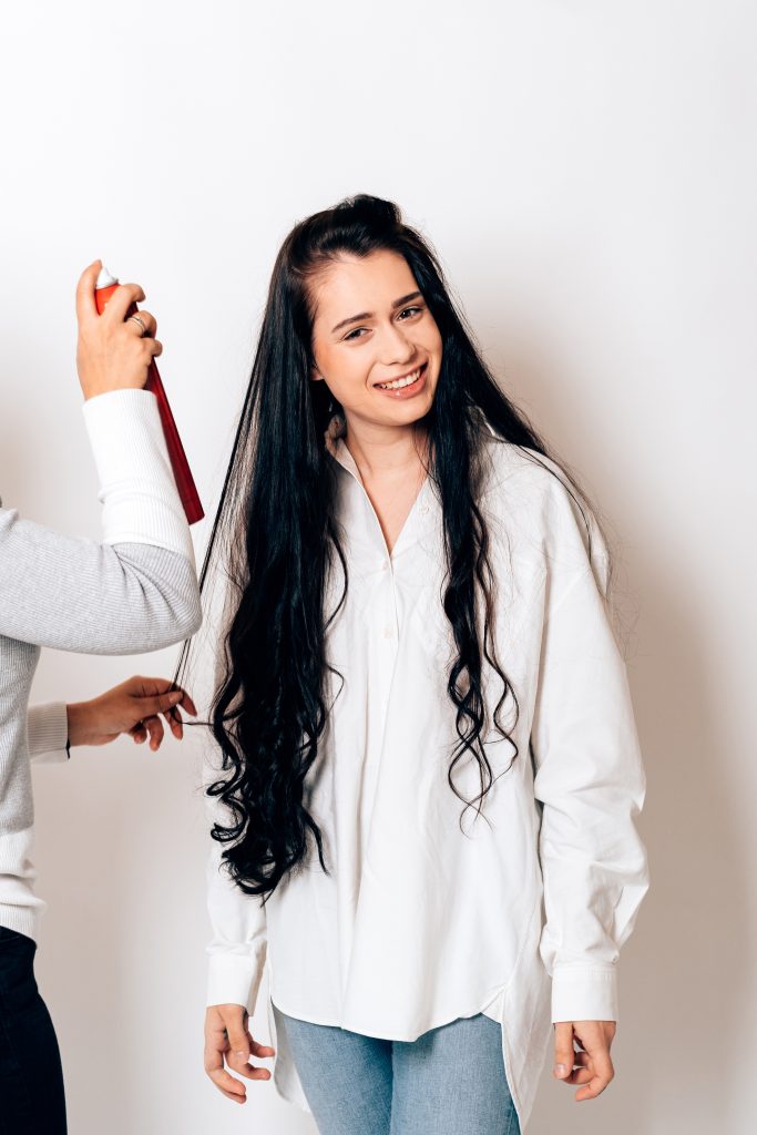 Hair Care Tips to Maximize Growth Potential. a smiling model gets her hair done by the hair stylist.