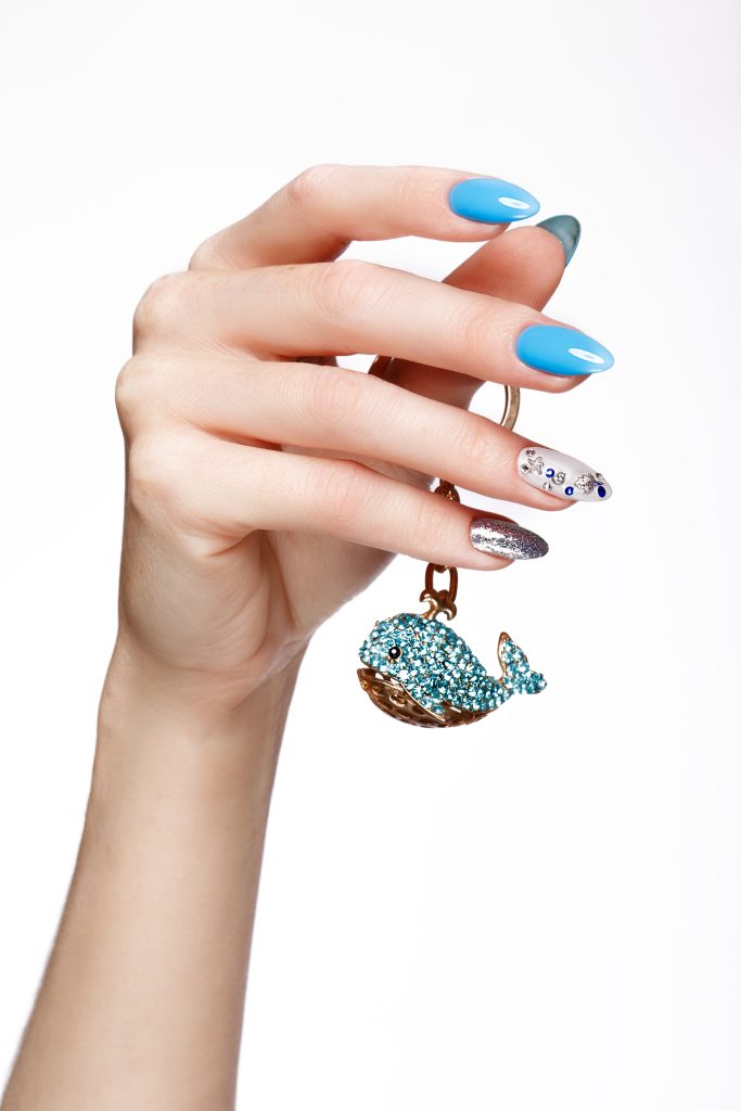 Beautiful summer blue manicure with crystals on female hand. Close-up. Picture taken in the studio. Trend Overview for 2025.