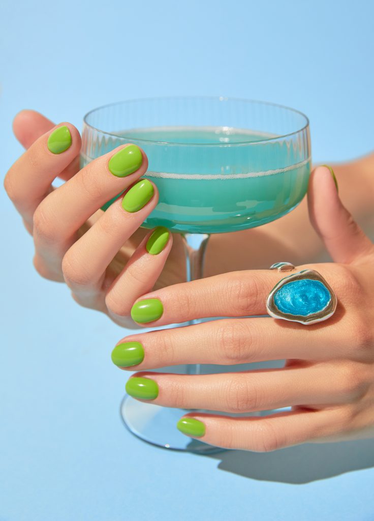 Beautiful woman's hand with summer green nail design holding glass. Manicure, pedicure beauty salon concept. Close up. Bold and Bright nails. neon nails. 2025 nails.