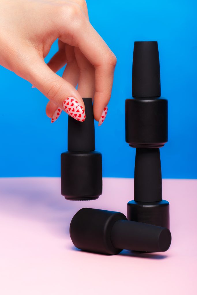 Black bottles of nail polish on a colorful background. Manicure design.