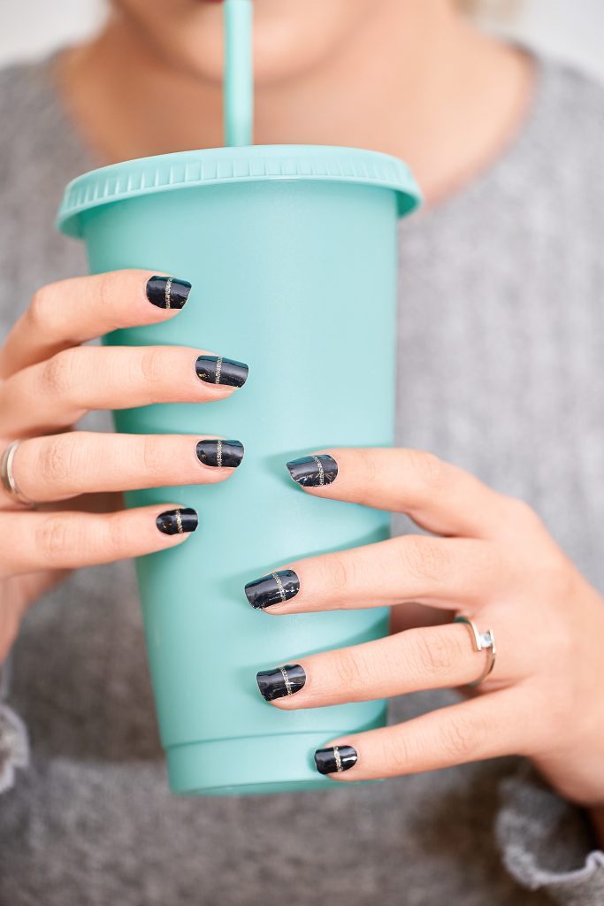 2025 Nail Designs. Close-up view of a woman holding a plastic cup with her stylish manicure nails. Manicure and beauty concept.