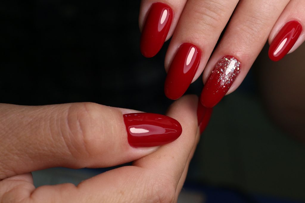 A closeup shot of red beautiful red manicure of female's long nails on a wooden background