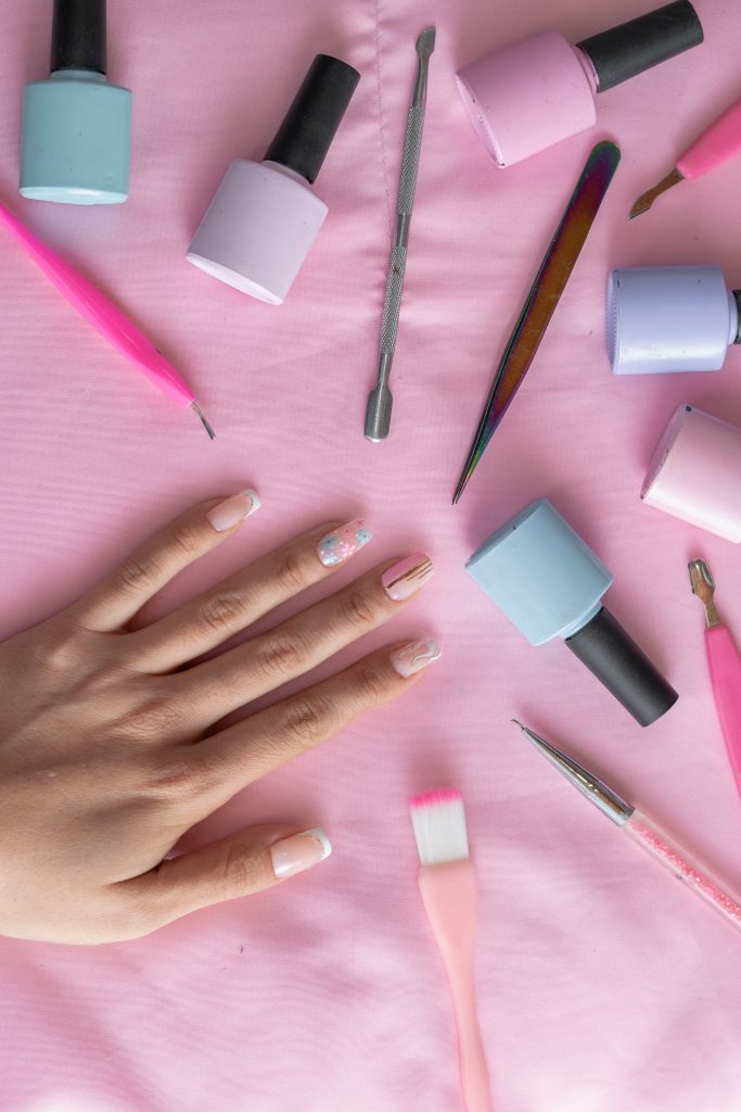 Nail Care Technology. Manicure and pedicure tools and products for home users. detailed view of a girl's hand with her nails decorated with a traditional manicure together with various manicure elements.