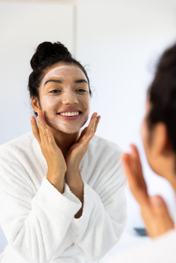 Happy biracial woman in bathrobe with face mask in sunny bathroom. Lifestyle, self care, beauty, skin and domestic life, unaltered. Tips for Maximizing Your Night Skincare Routine.