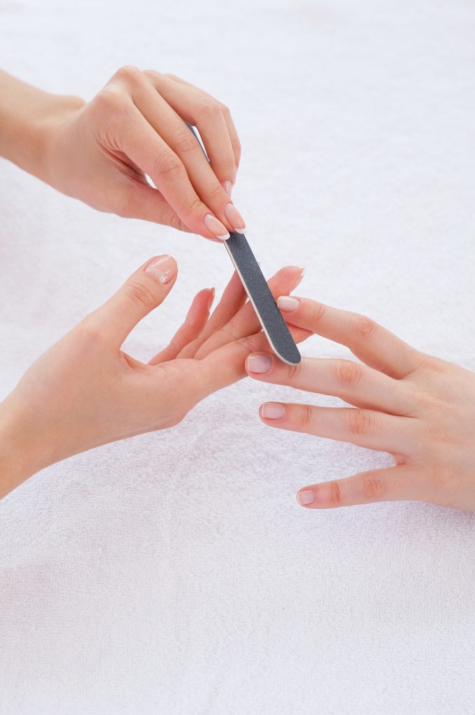 Nail care. Close-up of beautician polishing nails of female customer. Preventing Common Nail Issues.