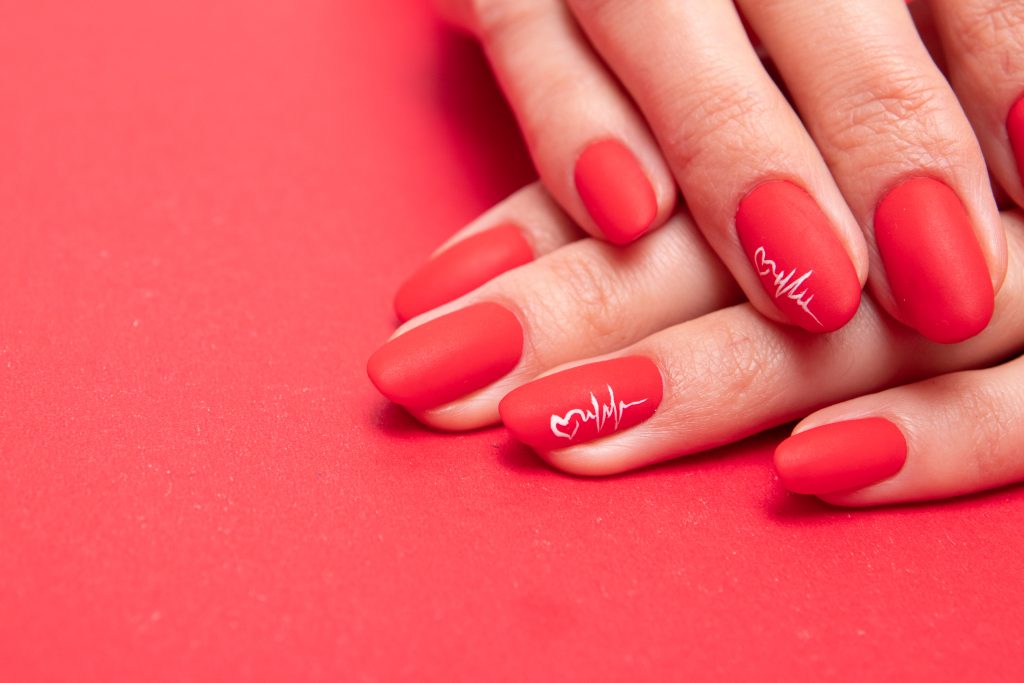 Red matte manicure on female hands for valentine's day. Matte Red nails