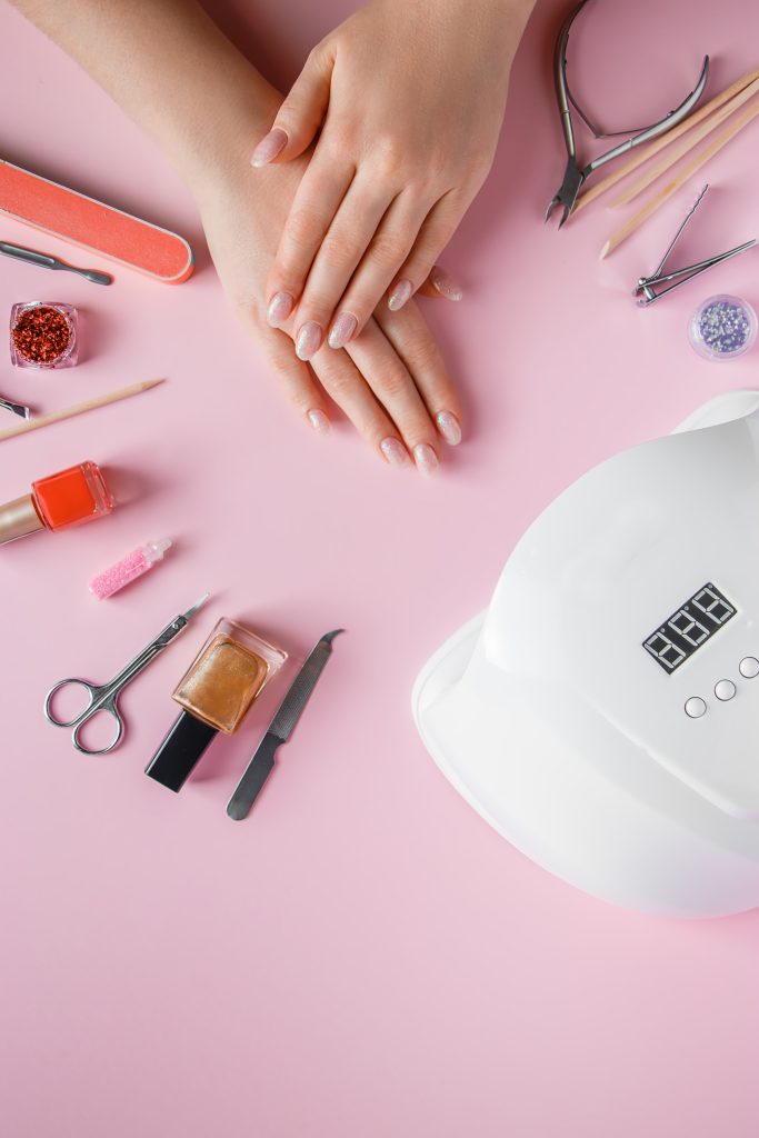 Spa procedure for nail care in a beauty salon. Female hands and tools for manicure on a pink background. Bodycare concept. Nail Care Technology. .