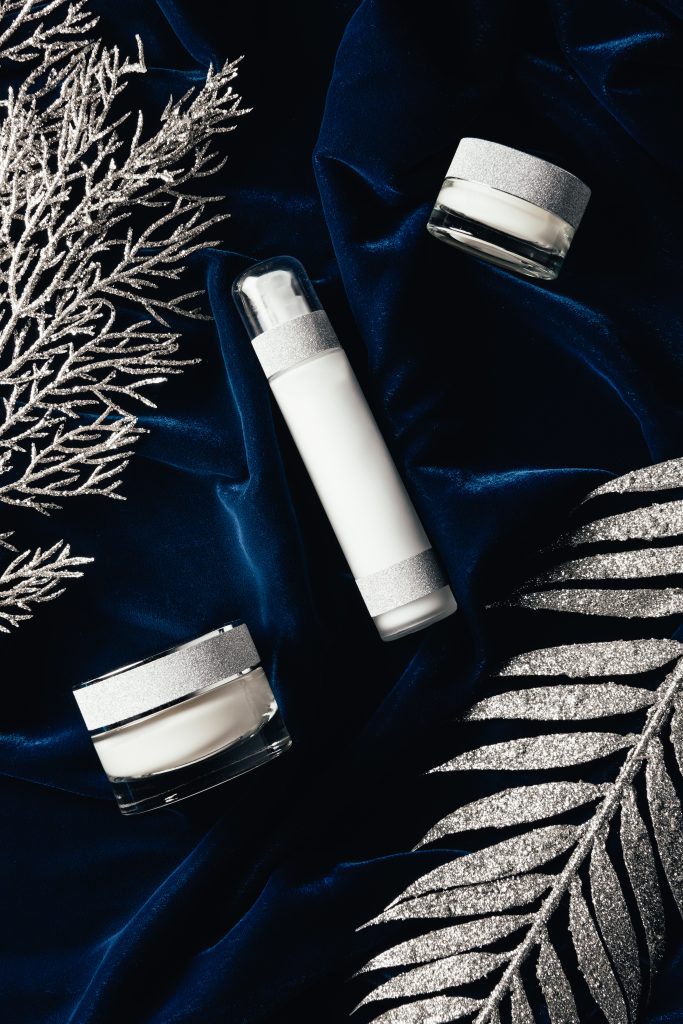 view from above of lotion and beauty cream between christmas silver branches on velvet surface. Nighttime Skincare. Essential Products for a Nighttime Skincare Routine.