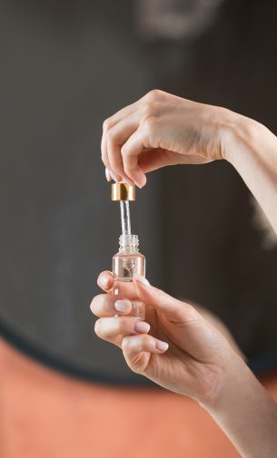 A woman holds a dropper and dropper with a drop of moisturizing serum for face and body skin care. Skin care concept.