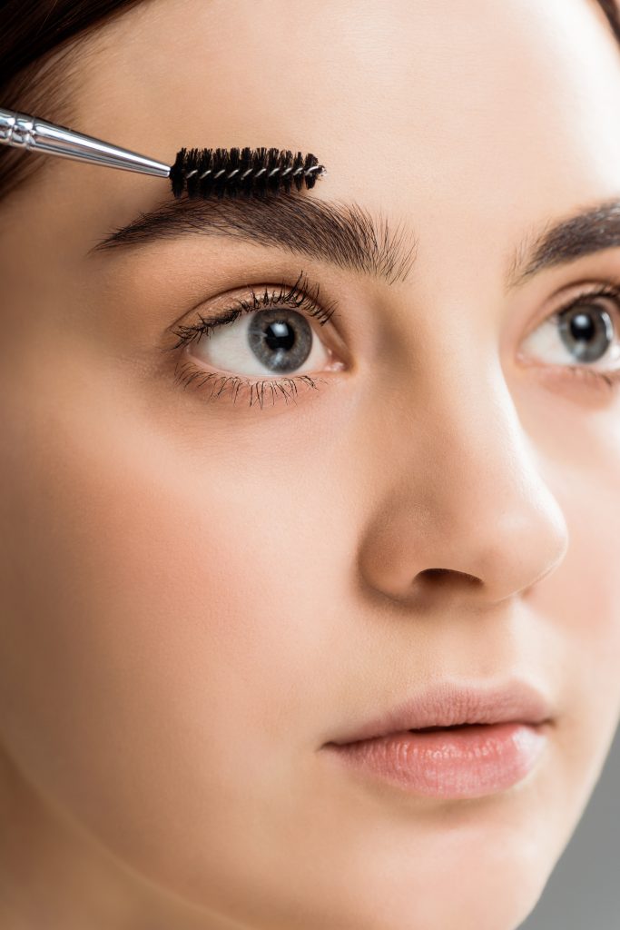 beautiful young woman styling eyebrow with eyebrow brush. 