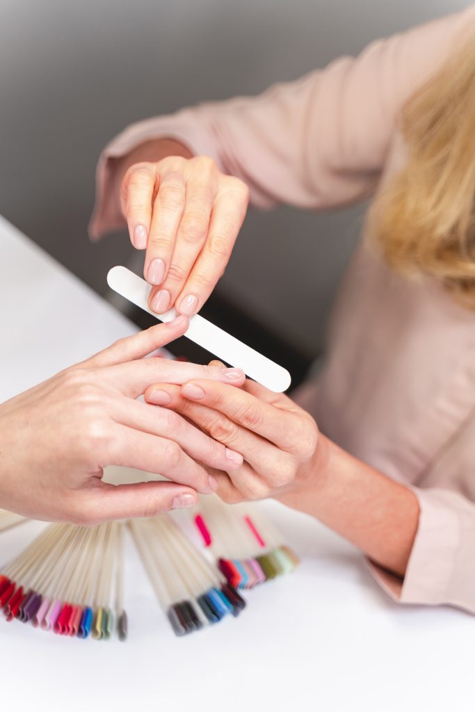 Effortless Nail Shaping Made Easy. Be careful. Focused photo on female hand that using nail file during beauty procedure. Beauty concept.