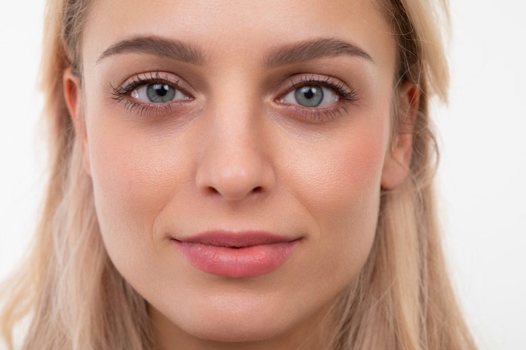 close-up portrait of a blonde of European appearance on a white background looking at the camera with a slight smile on her face. Banish Dark Circles for Good With Easy Steps!
