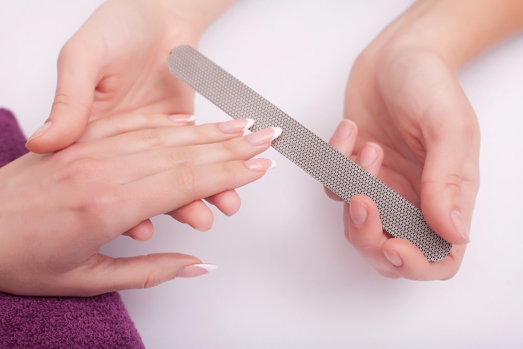 Closeup of four female hands. Professional manicurist doing nail polish. Effortless Nail Shaping Made Easy.