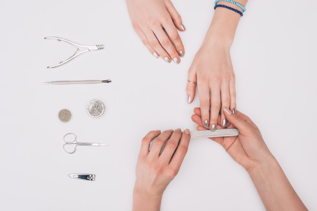 cropped image of manicurist filing nails to customer with nail file isolated on white. Effortless Nail Shaping Made Easy