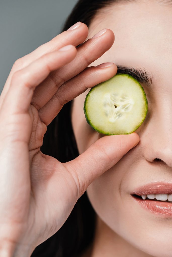 Cropped shot of woman holding a slice of cucumber in front of her eye. DIY Remedies for dark circles.