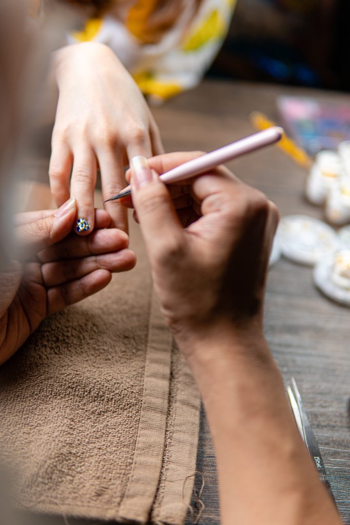 Tips for Long-Lasting Results. a woman makes a manicure to a client at home. Nail Art Home Services.