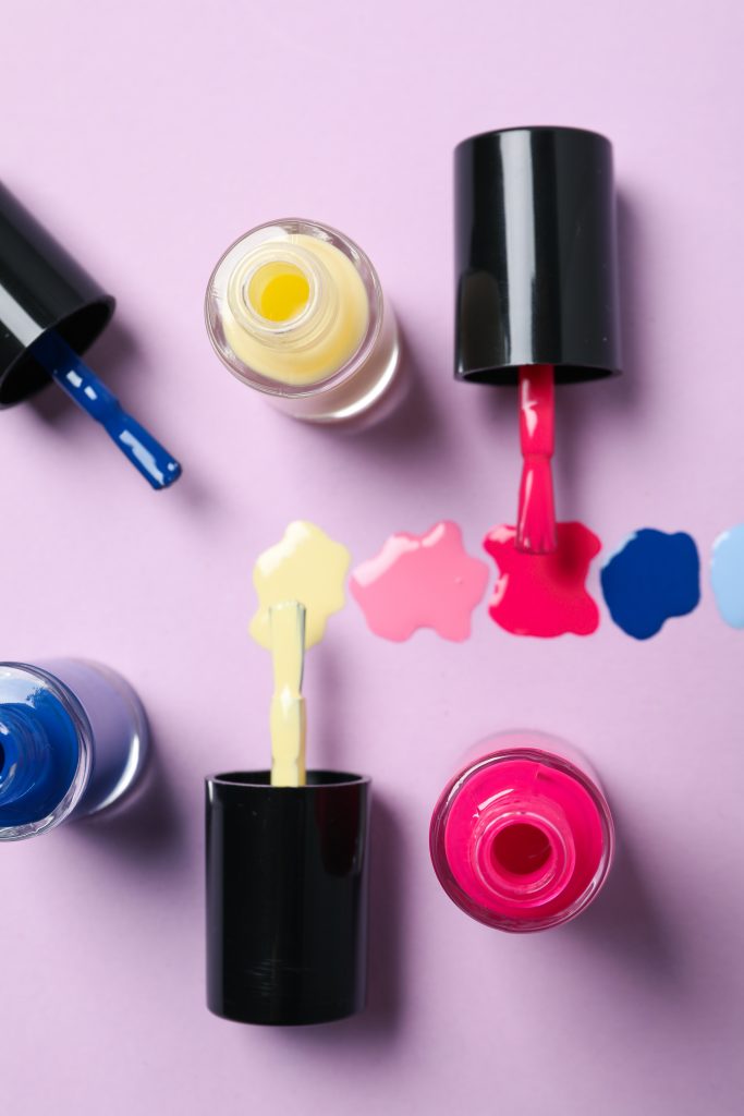 Top Products for Home Manicures. nail polish bottles. nail shades. Multicolored nail polishes with bones on a plain background.