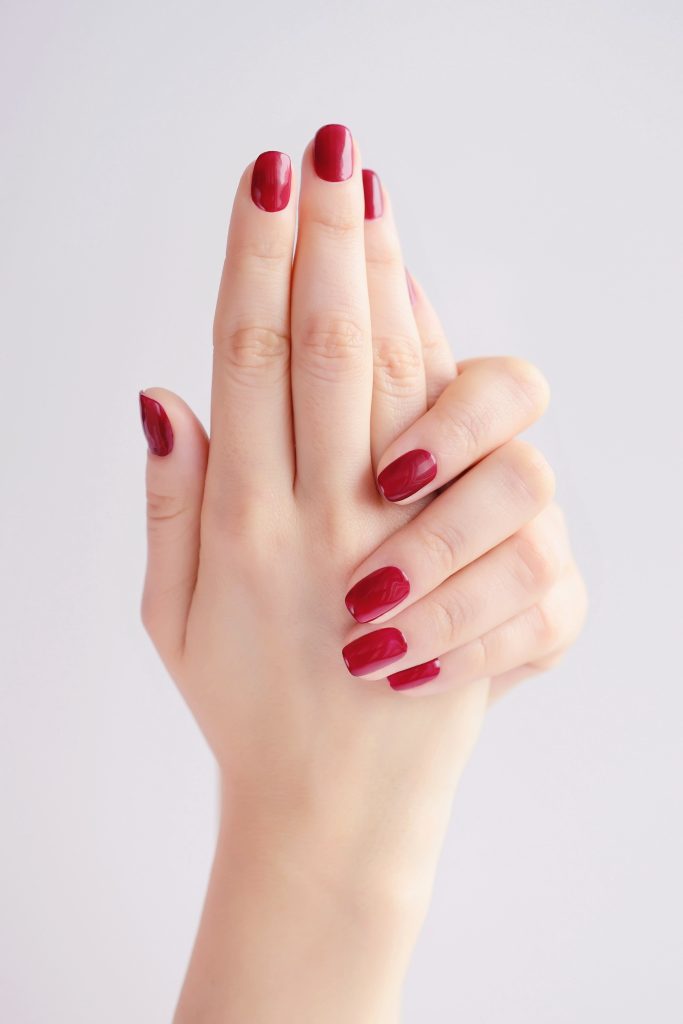 Closeup of hands of a young woman with red manicure on nails