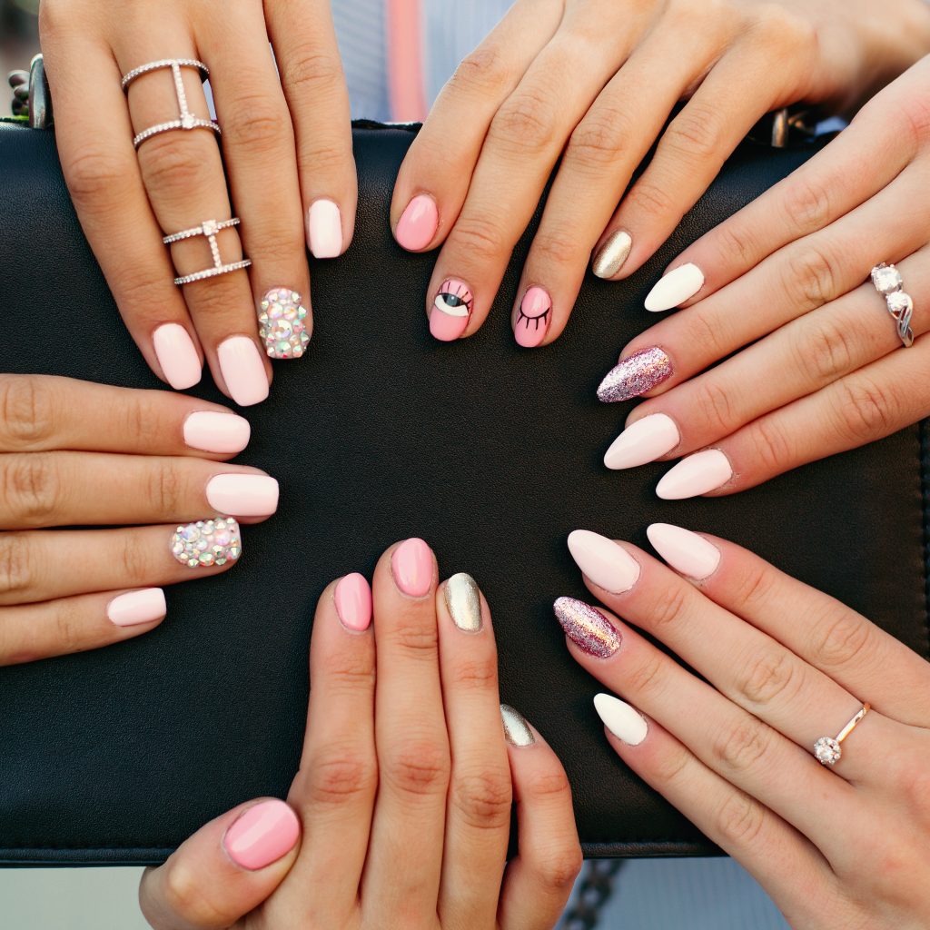 Close up of different fashionable and trendy manicure with design on girl s hands. Incognito female hands with elegance silver rings holding black leather hand bag. Concept of beauty and manicure. Nail Shapes.