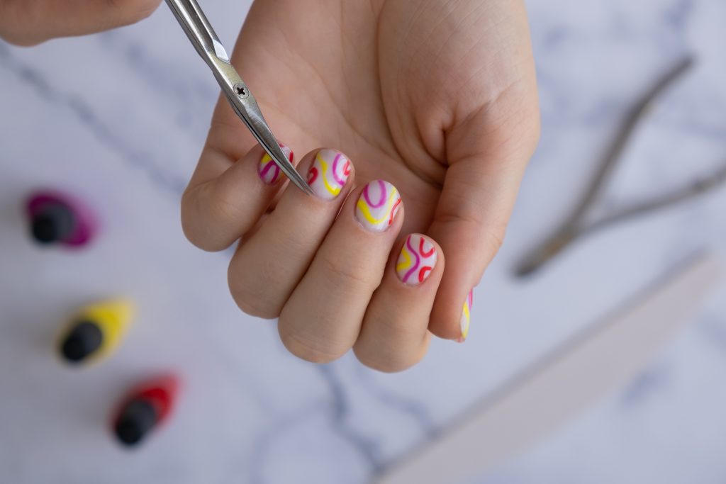 Manicured scissors Stylish colorful summer female nails. Modern trendy stylish Beautiful manicure. Cute pastel nail minimalistic design concept of beauty treatment. Gel nails. Skin care. Beautician