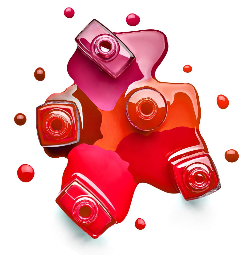 close up of a nail polish bottle and drop on white background