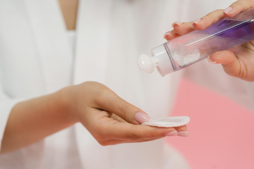 A faceless woman holding a nail cotton and a nail polish remover to remove her manicure. nail polish removers. nail polish. nail lacquer.