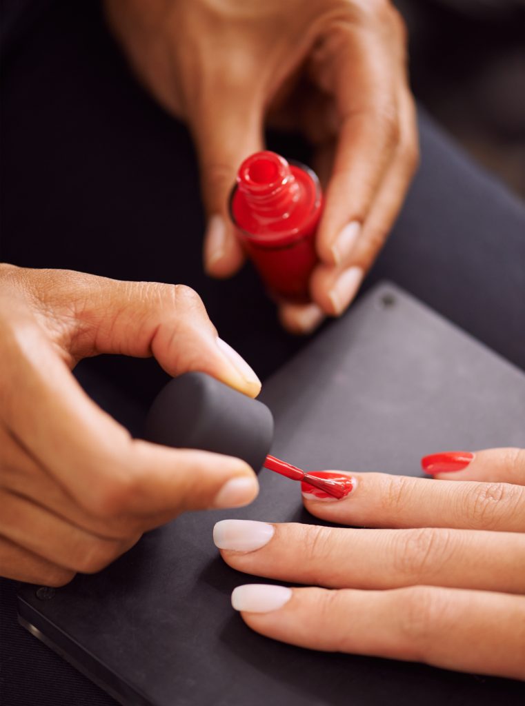 Ravishingly red nails. Closeup of fingernails being painted red