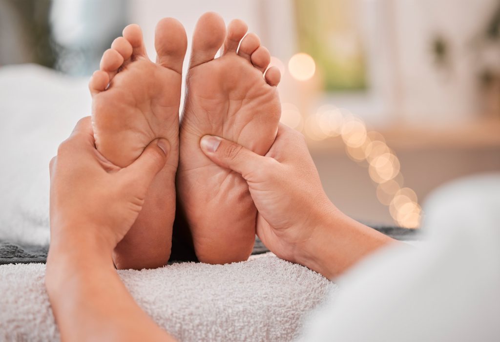 Spa, feet and massage for relax, wellness and health on bed with hands, luxury and physical therapy.