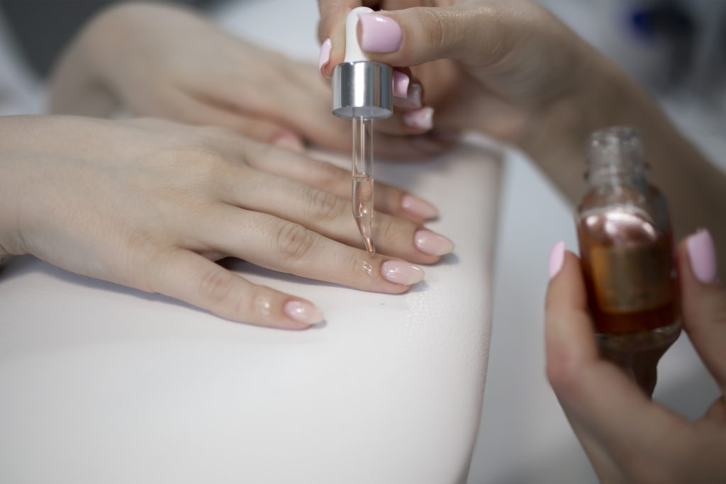 manicurist applying gel on the client's nail. protection cover. Cuticle oil. Cuticle oils. nail care.
