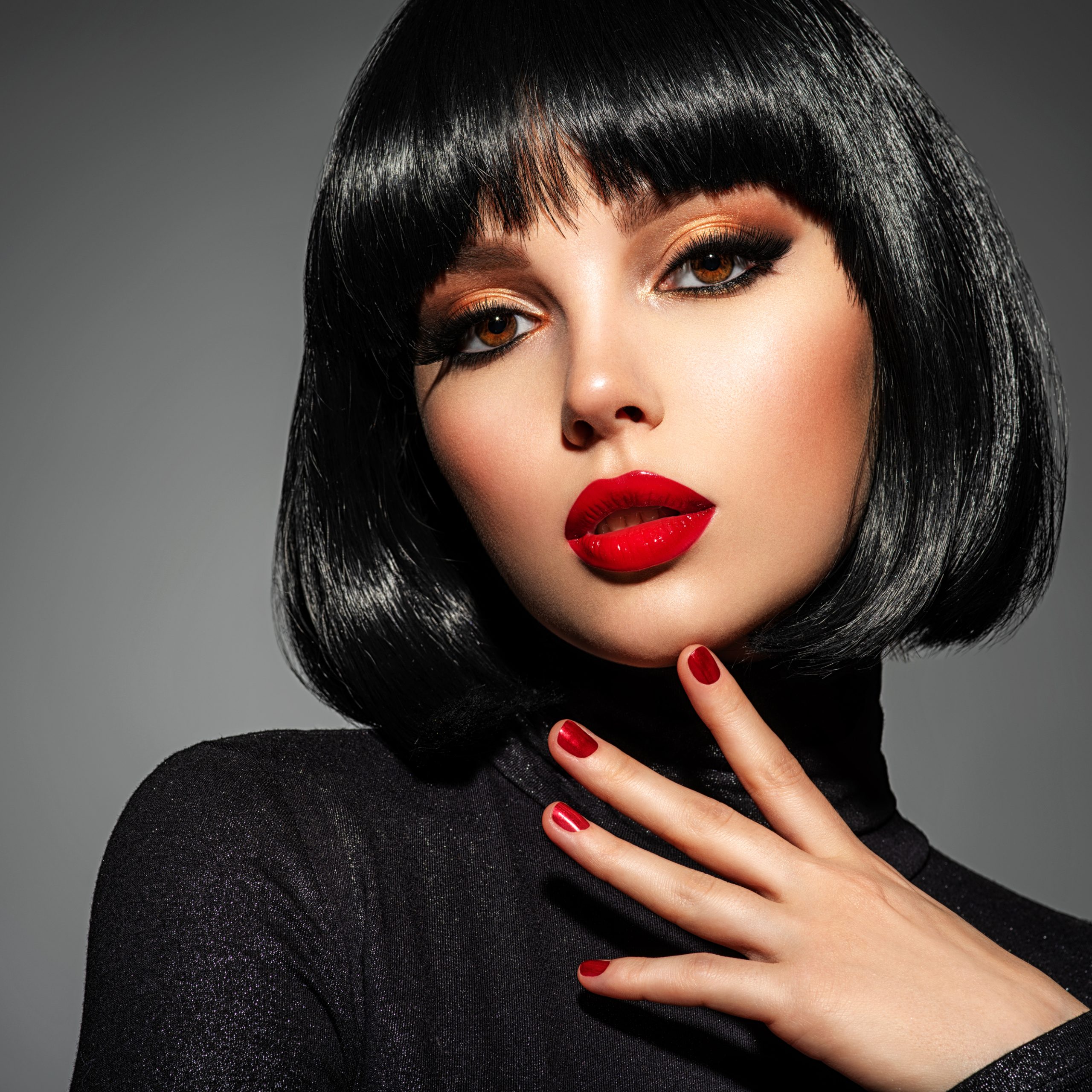 Beautiful brunette girl with red lips. Pretty young sensual woman with red nails. Closeup portrait of a model with bright makeup on a face. Attractive female posing at studio. The Best Matte Lipsticks That Stay All Day